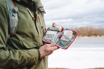 A bag with medicines, a first-aid kit in the hands of a tourist, tablets in a package, a patch for...