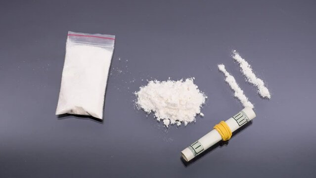 White powder in a transparent bag and a roll of dollar bills, the concept of drug use, addiction, illegal substances.
