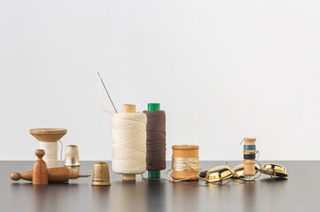 Spools of thread, needle, golden buttons and thimbles - 499285834
