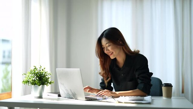 Attractive smart asian female adult using laptop computer working online from home at living room with cheerful freshness expression casual happiness lifestyle