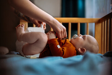 Hand gives baby boy with blue eye a pacifier.