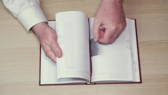 Male hands leaf through the diary on the table and take away the condom between the pages, the concept of planning safe sex