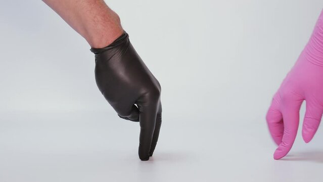Male and female hands in black and pink rubber gloves meet and take a condom. Dating, safe sex, contraception, birth control, STD prevention.