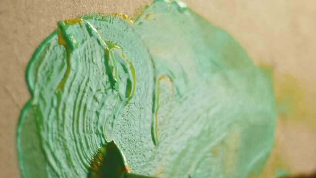 A wide brush swirls ink on a wooden board, paints an abstract picture with acrylic or oil paint.