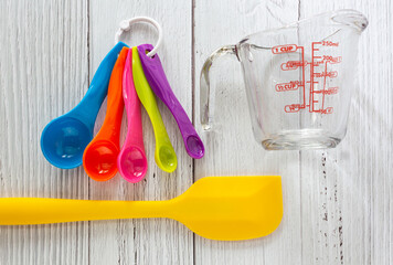 Set of measuring spoons made from colorful plastic, measuring cup made from glass, digital scale...