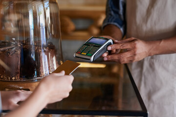 Put it through my cheque account. Closeup shot of a customer making a credit card payment in a cafe.