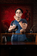 Portrait of white asian gardener adult man short hair wear black shirt jean apron wrist watch and glasses considering Stephania erecta standing behind plant seed bar with red women painting