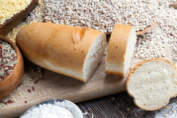 wheat baguette on the table with flour and various plant grains
