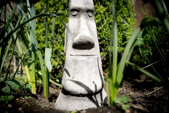 Focus of the eyes of a home-made stonework ancient face depicting an ancient civilisation. Seen in a freshly dug flower bed, part of a secret garden.