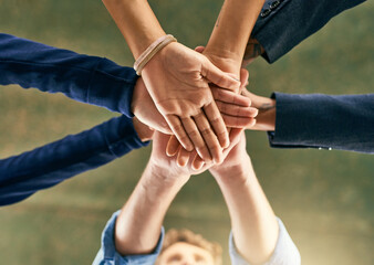 Lets get further together. Closeup shot of a group of people joining their hands in a huddle.