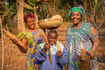 group of African farmers have fun in the fields, they have hoes in their hands and are ready to plow the field, child with the basket of crops on his head - obrazy, fototapety, plakaty