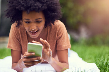 I never saw anything like this app. Shot of a young man texting while relaxing at the park.