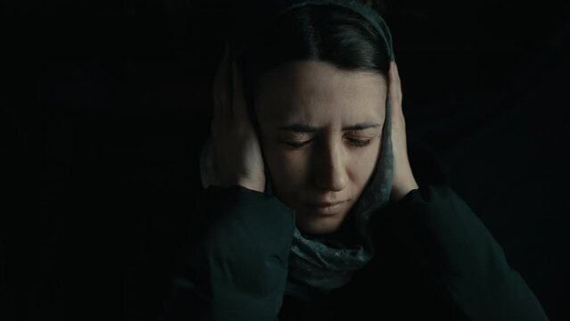 Woman in the basement covering her ears with her hands