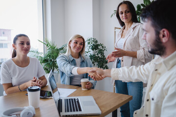 Man and woman shaking hands to each other while making deal in office