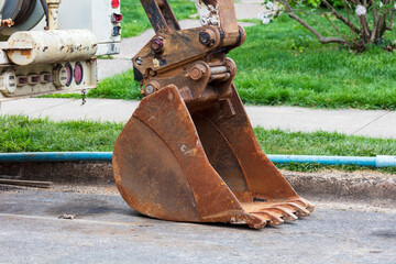 Rusty Excavator Bucket parked by street curb