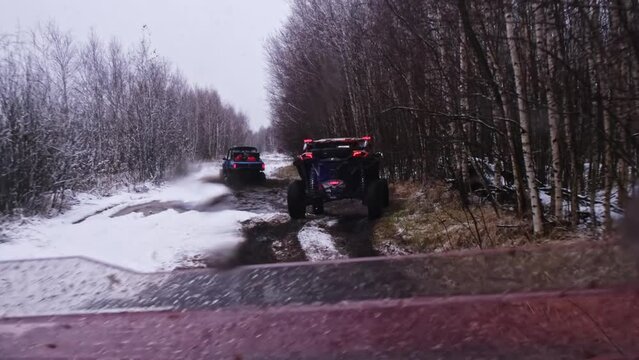 A group of UTV buggies drive through mud and puddles