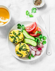 Baked omelet spinach cakes, fresh vegetables and green tea on a light background, top view