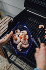 woman using tongs to take prawns off barbecue