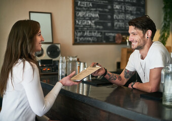 Personally, Id recommend this one. Shot of a friendly young bartender helping a customer with her order across the bar counter.