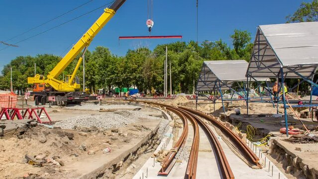 Yellow construction telescopic mobile crane moving tram rails timelapse.