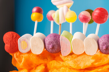 Multi-colored candies on a stick, blue background.Many colorful lollipops (Chyupa-Chyups) on a blue...