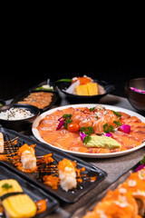 Fototapeta na wymiar Sashimi sushi set with soy on black background.Assorted sushi set served on dark stone slate background. Top view