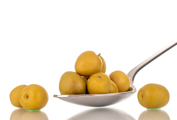 Several green pitted olives on a metal spoon, macro, isolated on white.