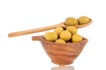 Several green pitted olives in a wooden cup and with a wooden spoon, macro, isolated on white.