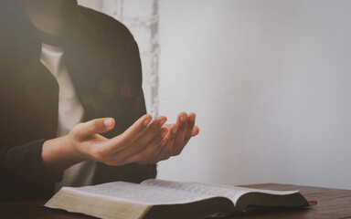 Women pray for God's blessings for a better life.  Christian Life Crisis Pray to God  Human hands praying to God with the Bible.  Believe in the good.  Hold hands in prayer on a wooden table.