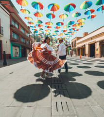 Dancers of typical Mexican dances from the central region of Mexico, doing their performance in the street adorned with colored umbrellas.