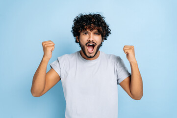 Win, triumph. Excited amazed indian or arabian guy, in t-shirt, rejoices in success, victory, win,...