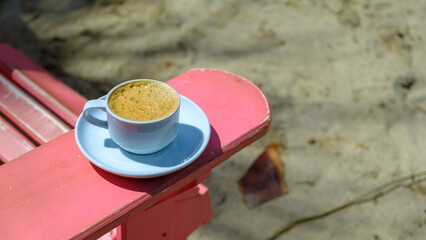 A coffee break while on vacation in the garden of the hotel. Coffee in a mug standing on the table in the garden. A coffee cup standing on the table in the natural area.