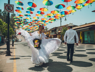 Dancers of typical Mexican dances from the region of Veracruz, Mexico, doing their performance in the street adorned with colored umbrellas.