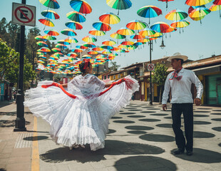 Dancers of typical Mexican dances from the region of Veracruz, Mexico, doing their performance in the street adorned with colored umbrellas.
