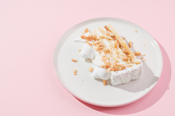 a piece of cake with nuts on a pink plate and a pink background