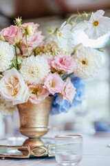 Blue wedding decor. Festive table decorated with flowers on the center, candles, silverware and plates with silk napkins on dusty blue tablecloth