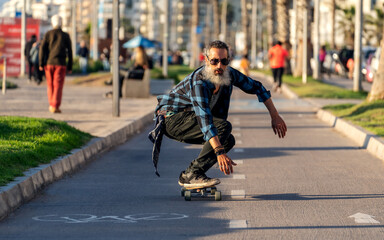 senior latin beard man skateboard in the street of La Serena