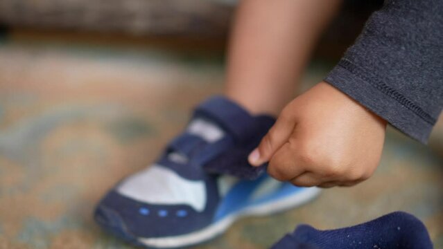 Child on doorstep putting shoes by himself