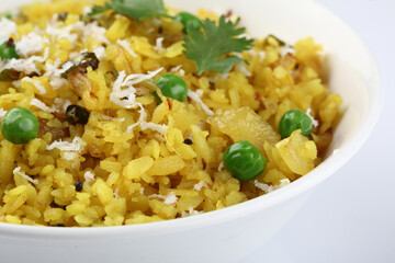 Kande Pohay OR Aloo Pohe is a popular Indian breakfast recipe made using Flattened rice, usually served with hot tea. Served in a bowl over moody background. Selective focus