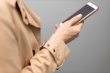 woman's hand in a raincoat holding a mobile phone