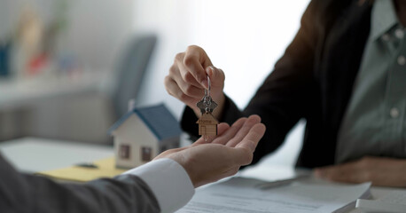 Close up hand of home,apartment agent or realtor was holding the key to the new landlord,tenant or rental.After the banker has approved and signed the purchase agreement successfully.Property concept.