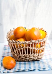 Orange organic tomatoes in wicker basket on a windowsill. Sunlight. Healthy nutrition. Harvest. Minimalistic simple neutral light template. Superfood. Organic eco health care. Vitamin nutrition.