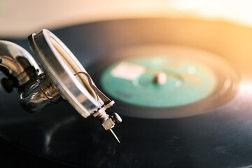 needle of an old portable gramophone with a powder-covered vinyl record