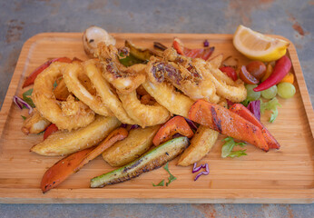 Tempura calamari with vegetables on a wooden plate.