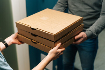 Close-up high-angle view of female customer receiving carton boxes with takeaway at home from...