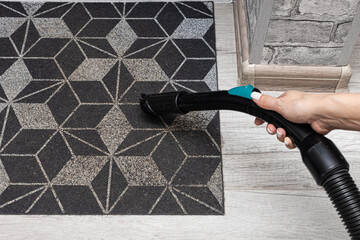 a woman's hand vacuums a dirty carpet with a nozzle