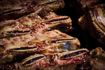 juicy beef rib and pork rib slowly being made on the grill on the fire at a gas barbecue