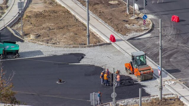 Construction site of avenue with asphalt paver, roller and truck aerial timelapse.
