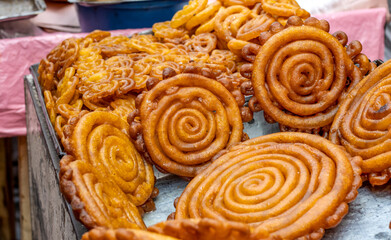 Various designed fried cakes or jalebi on a street food market close up