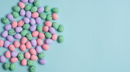 Colorful Easter Egg side border over a pastel blue paper background. Copy space.